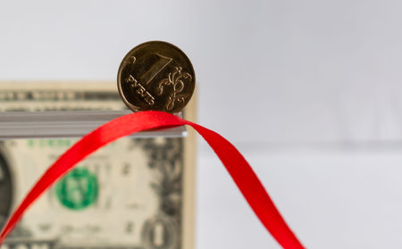 One ruble coin close-up on blurred background of red ribbon and One dollar banknote