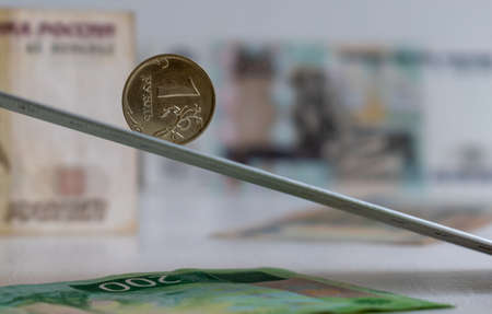 One ruble coin on inclined flat on blurred background of Russian rubles banknotesの写真素材