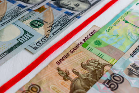 Red ribbon separating banknotes of US dollars and Russian rubles. Focus at the center of imageの写真素材