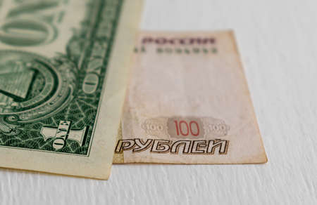 One dollar banknote and One hundred rubles banknote close-up on blurred background. Focus on foregroundの写真素材