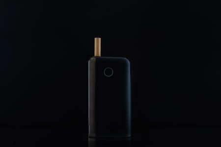 Black gadget for using tobacco sticks on black backgroundの写真素材
