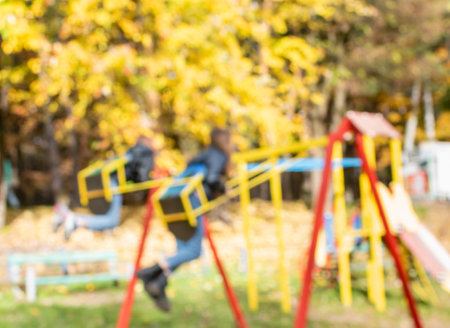 Defocused image of bright yellow foliage on playground on sunny autumn day in parkの写真素材