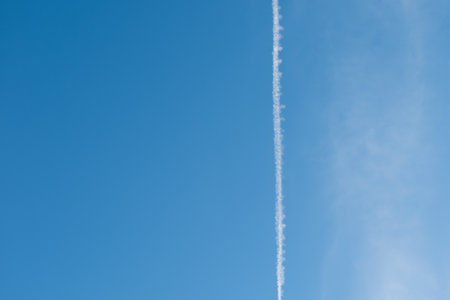 White trail of a jet plane on background of blue skyの写真素材