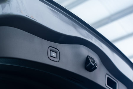 Button for automatic electric opening and closing of trunk door of new passenger car close-up on...