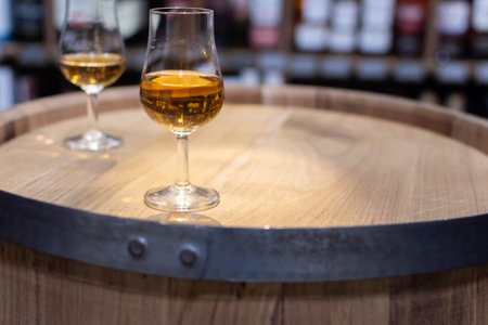 Whiskey glass close-up on oak barrel on blurred colorful background