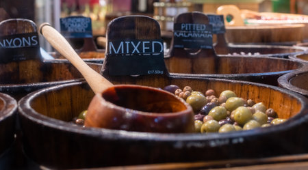 Fresh delicious mixed olives in wooden barrel with price tag in euros per kiloの写真素材