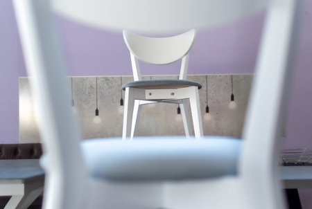 Cabinet furniture. Comfortable white chair framed by another chair close-up in kitchen interior
