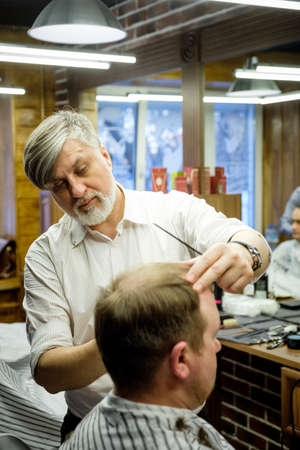 MOSCOW, RUSSIA - MAY 24, 2018: Russian barber Sergei Urazov does a haircut to the client.のeditorial素材