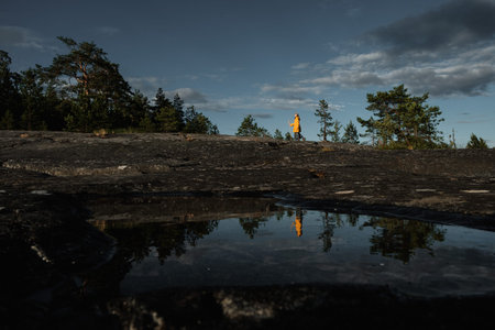 A girl in a yellow raincoat with a staff stands on the shore of Lake Ladoga