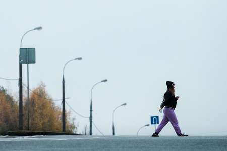 MOSCOW, RUSSIA - NOVEMBER 02 2020: A girl with a mask in her hand crosses the road to Yasenevoのeditorial素材