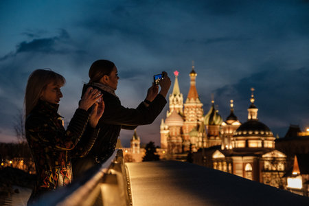 MOSCOW, RUSSIA - APRIL 17 2021: Girls taking pictures by smartphone in the evening in Zaryadye parkのeditorial素材