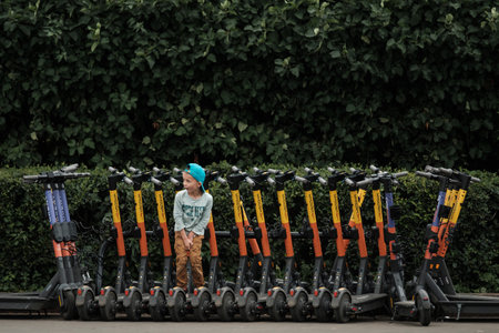 MOSCOW, RUSSIA - JULY 3 2021: A child stands in the parking lot of electric scootersのeditorial素材