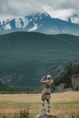 Girl with binoculars standing in the mountains of the Altai Republic.