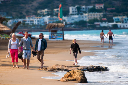 MALIA, CRETE, GREECE - OCTOBER 22 2012: A family walking along the seashoreのeditorial素材