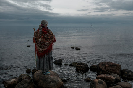 A girl with a staff standing on the shore of Lake Ladoga