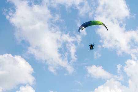 One paraglider is flying in the blue sky against the background of clouds. Paragliding on a sunny day. Space for text.の写真素材