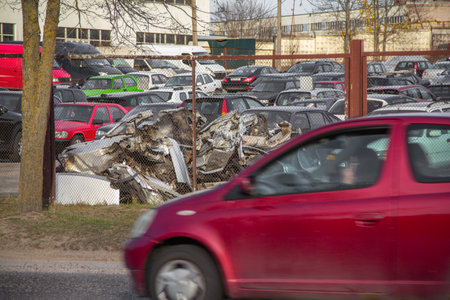 Broken gray car in the parking lot. Car parking behind a fence. moving car in the foreground. With copy space for text or design. The concept of traffic rules and safety.の写真素材