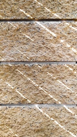 Textured stone blocks on the facade of the house with beautiful sun glare. vertical frame.の写真素材