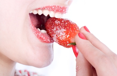 Girl biting a juicy strawberries in sugarの写真素材