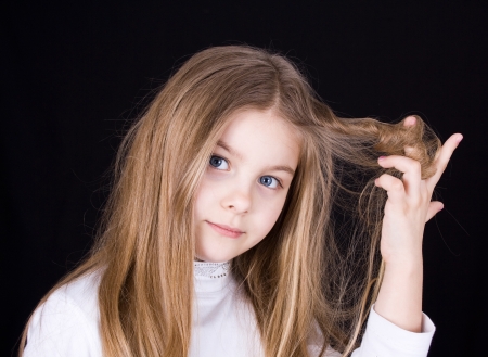 girl playing with hair on a black backgroundの写真素材