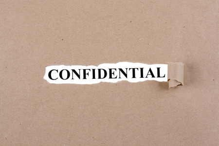 Word confidencial appears under the torn brown paperの写真素材