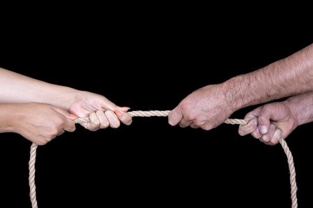 Two hands pulling a rope. All isolated on black background.の写真素材