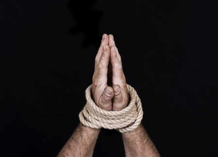 Men's hands tied a rope isolated on a black backgroundの写真素材