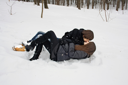 Man and woman in captivity of love, kissing lying on the snowの写真素材