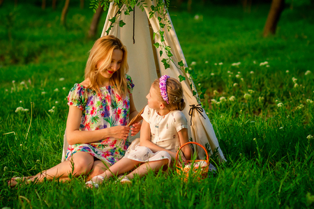 Beautiful young lady and her cute children posing in the green park at bright summer dayの写真素材