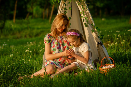 Beautiful young lady and her cute children posing in the green park at bright summer dayの写真素材
