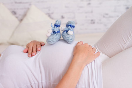 Pregnant woman holding blue baby booties, expecting boy