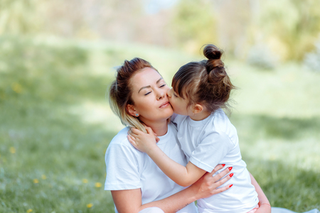 Daughter kisses mom on the cheek while playing outdoorsの写真素材