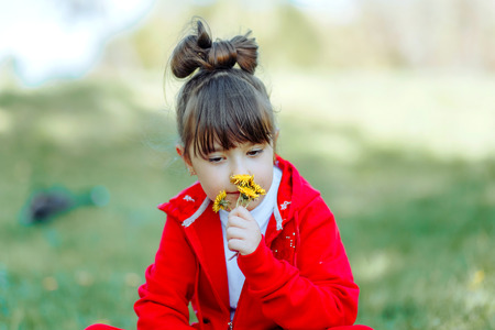 Girl in a burgundy dress sniffing wildflowersの写真素材