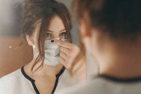 Light hair woman puts on medical mask for protection against virusの写真素材