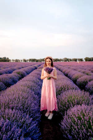 Beautiful woman admires a bouquet of lavender in a sunset, lavender fieldの写真素材