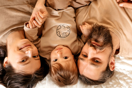 Family, dad, mom and son lie on the bed look at the cameraの写真素材