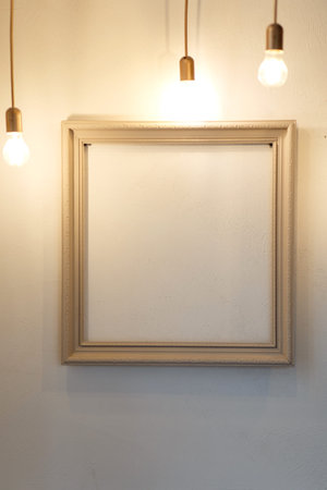 Empty frame on the wall illuminated by light bulbs