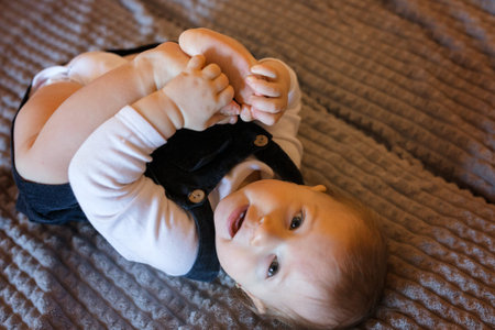 Little girl playing with her legs while lying on the bed