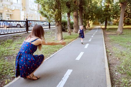 A child runs along the path in the Park to meet his motherの写真素材