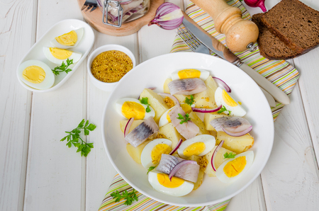 Potato salad with salted fish, boiled eggs, onions and parsley leaves.の写真素材