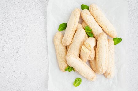 Homemade traditional Italian cookies Ladyfingers (savoyardi) on baking paper on a light stone background. Biscuits for tiramisu. Horizontal, Copy space. Top view.の写真素材