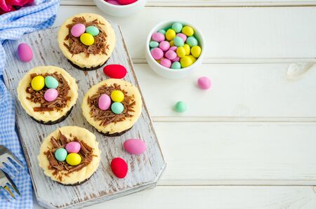 Easter mini brownie cheesecake Bird's Nest with chocolate and candy eggs. Easter dessert. Funny food idea for children. Horizontal orientation. Top view, copy space.の写真素材