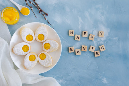 Easter cookies in the form of Easter egg with powdered sugar and lemon cream on a white plate on a...
