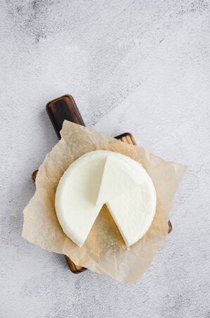 Homemade fresh soft cheese brynza or feta on a wooden cutting board on a gray background. Vertical orientation. Copy space. Top viewの写真素材