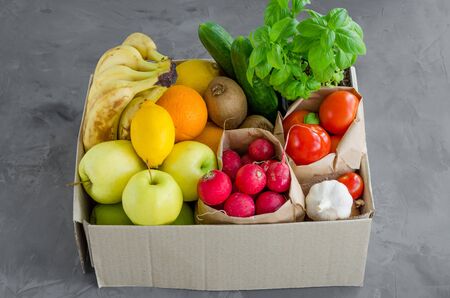 Donation box with fresh organic fruits, vegetables and herbs on a concrete background. Proper nutrition. Delivery healthy food to the home. Horizontal orientationの写真素材
