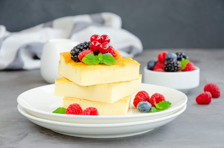 Homemade cottage cheese casserole with fresh berries and mint on top on a white plate. Healthy...