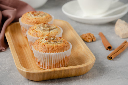 Banana muffins with oatmeal, walnuts and cinnamon on a wooden plate on gray concrete background....