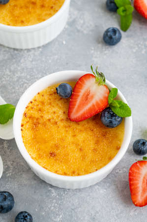 Creme brulee. Traditional French vanilla cream dessert with caramelised sugar and fresh berries on topの写真素材