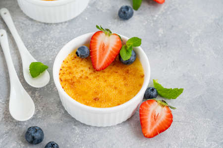 Creme brulee. Traditional French vanilla cream dessert with caramelised sugar and fresh berries on topの写真素材