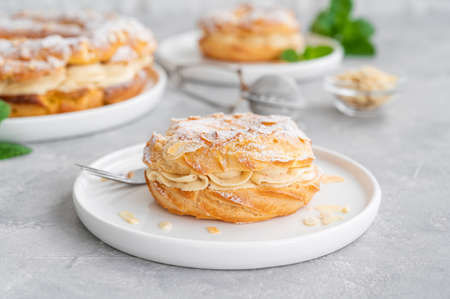 French traditional cake Paris Brest with praline cream, powdered sugar and almond petals on top on a gray concrete background. Copy spaceの写真素材